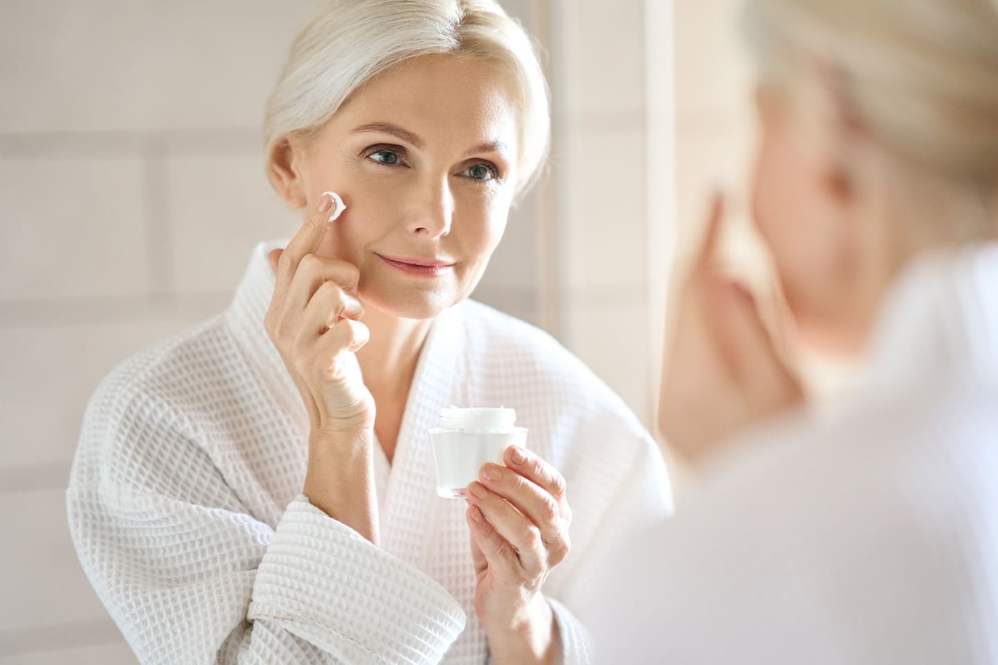 Une femme se met de la crème à base de collagène