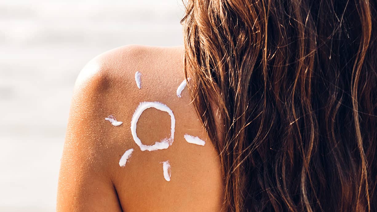 Crème solaire sur le dos en été au bord de la plage